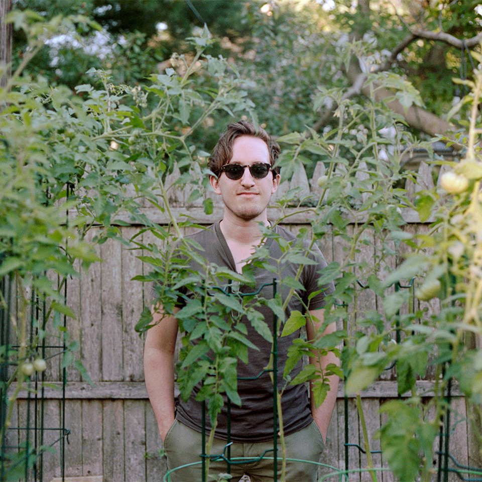 Andrew Kuhar in his garden, surrounding by vining tomato plants.